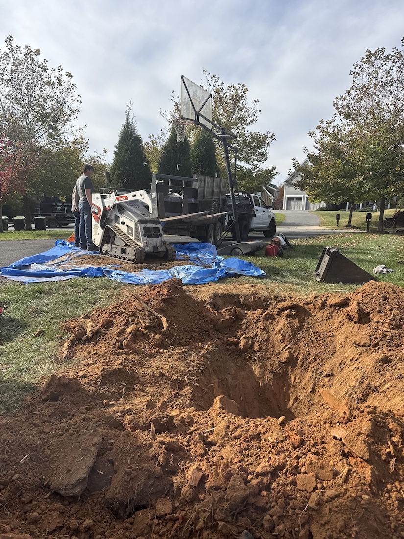 Bobcat track loader excavating a stump and root ball from a residential yard