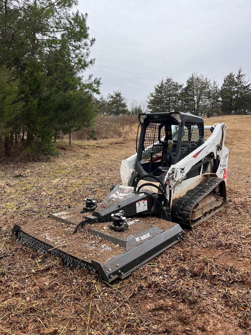 Mini skid steer moving brush and debris during a Favorite Tree Service job